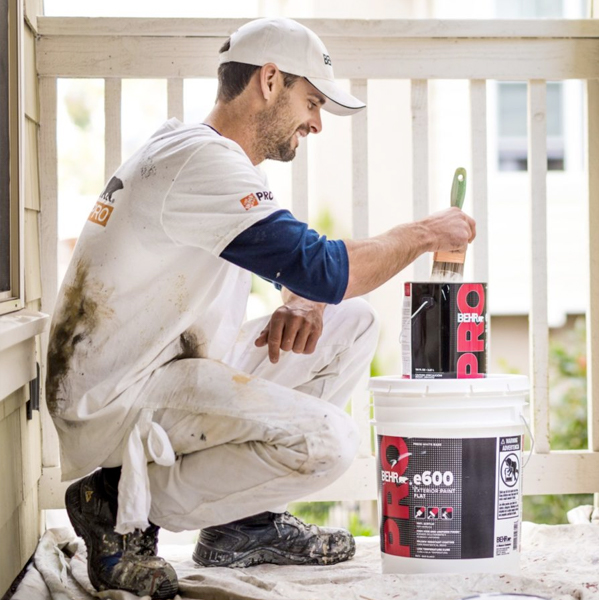Painting contractor outside on a deck with Behr paint