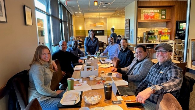 A group of people gathered together at a table for a partner networking event in Portland.